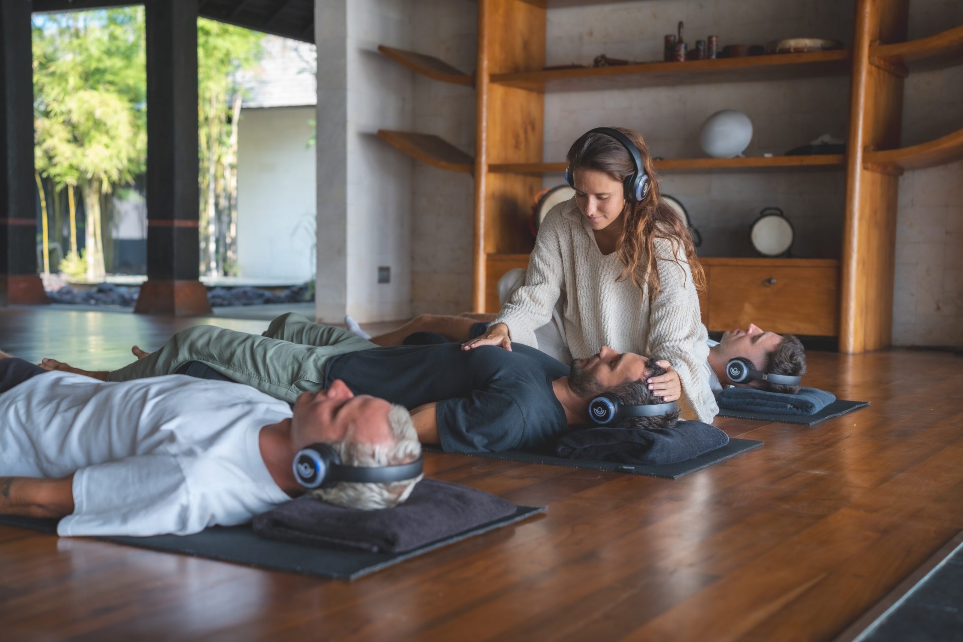 Woman resting peacefully with headphones during an in-person guided breathwork session